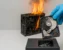 Eine verbrannte Festplatte wird von einer Person mit blauen Handschuhen gehalten, während im Hintergrund ein PC-Gehäuse brennt – Symbolbild für Datenschutz nach einem Brand.